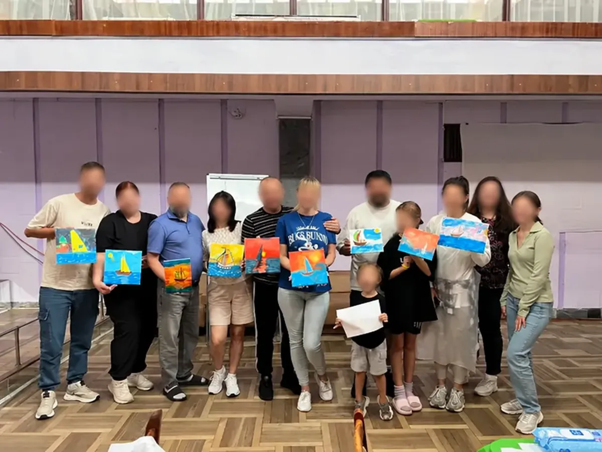 Participants holding their paintings after a creative activity